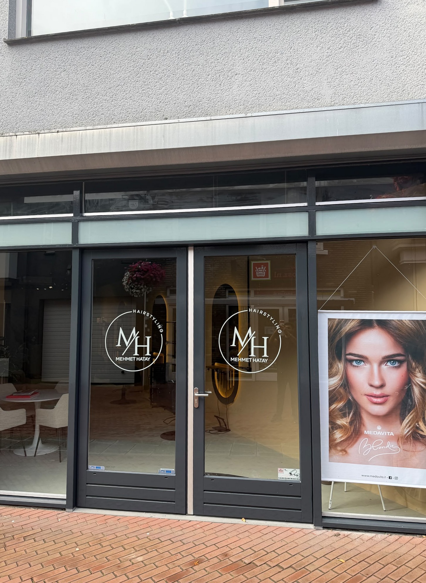De pui van MH Hairstyling aan de Nieuwstraat, met het MH-logo op de ramen